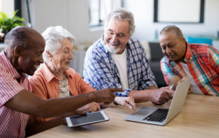 Group of happy seniors using a tablet and laptop
